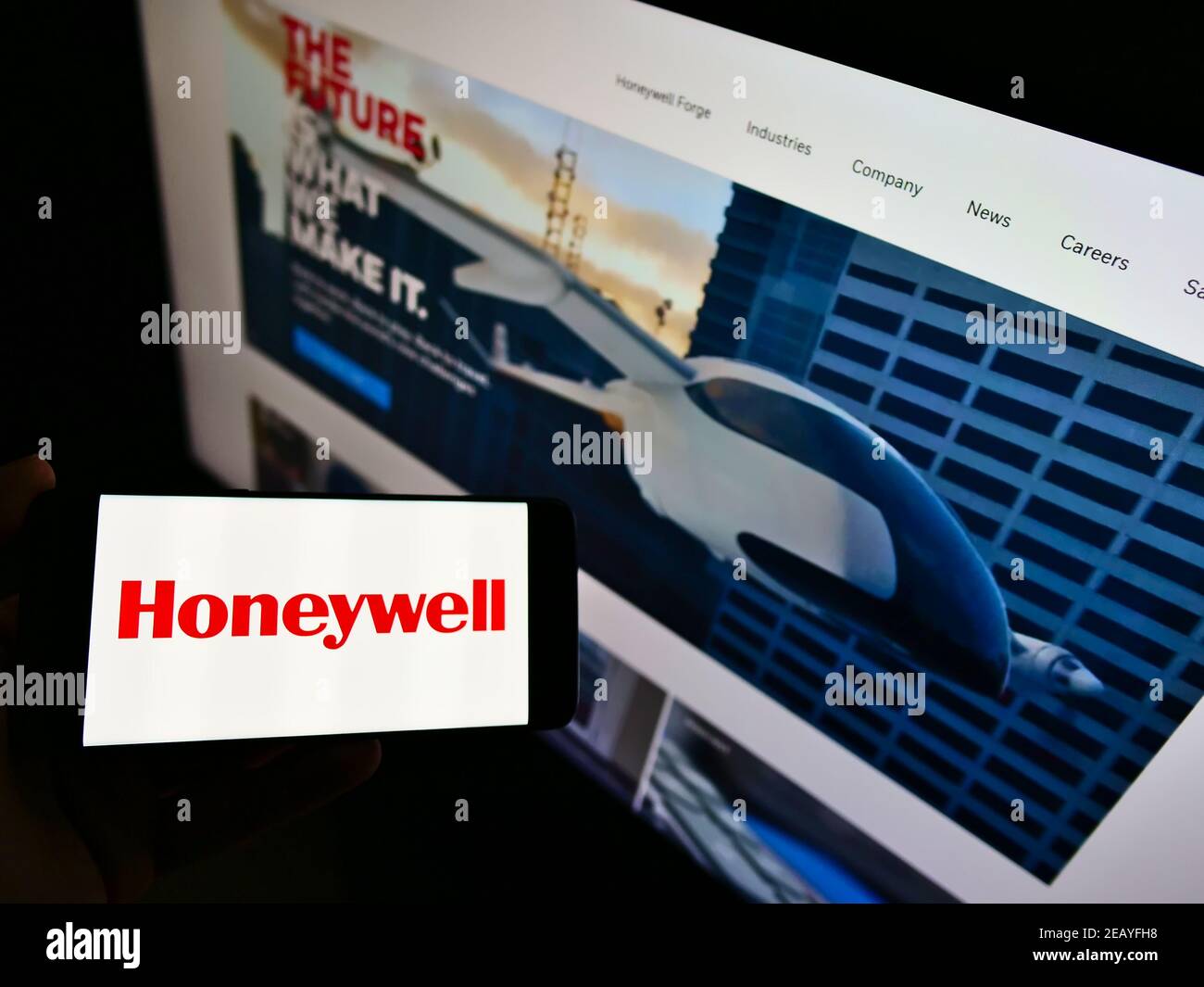 Person mit Mobiltelefon und Logo des amerikanischen Mischkonzerns Honeywell International Inc. Auf dem Bildschirm vor der Webseite. Konzentrieren Sie sich auf die Telefonanzeige. Stockfoto