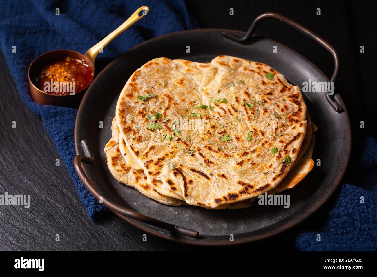 Food Konzept Spot Fokus hausgemachte Paratha, Parotta oder Porotta geschichteten Fladenbrot auf schwarzem Hintergrund mit Kopierraum Stockfoto