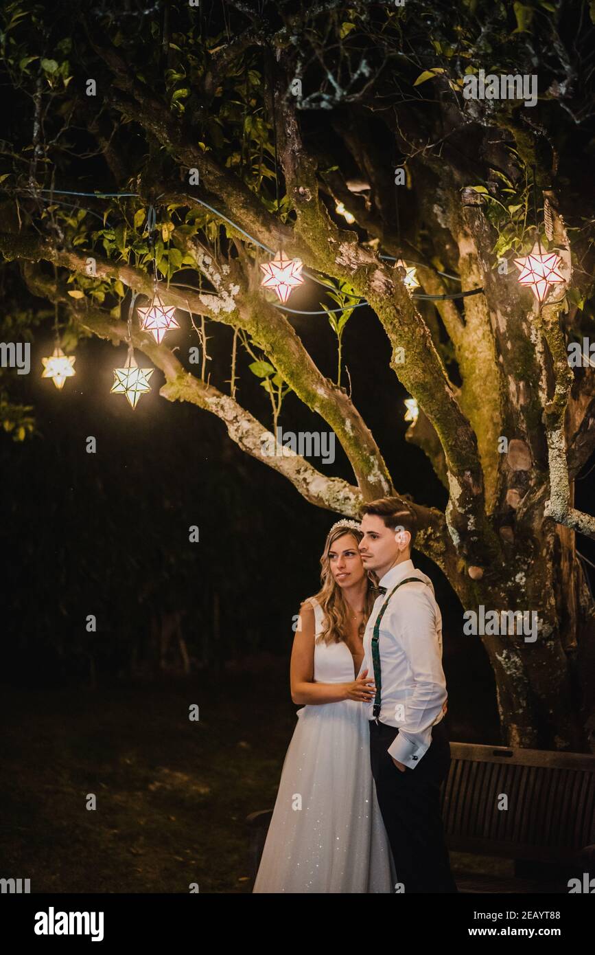 Paar unter einem Baum mit Pendelleuchten auf ihrer Hochzeit Tag Stockfoto
