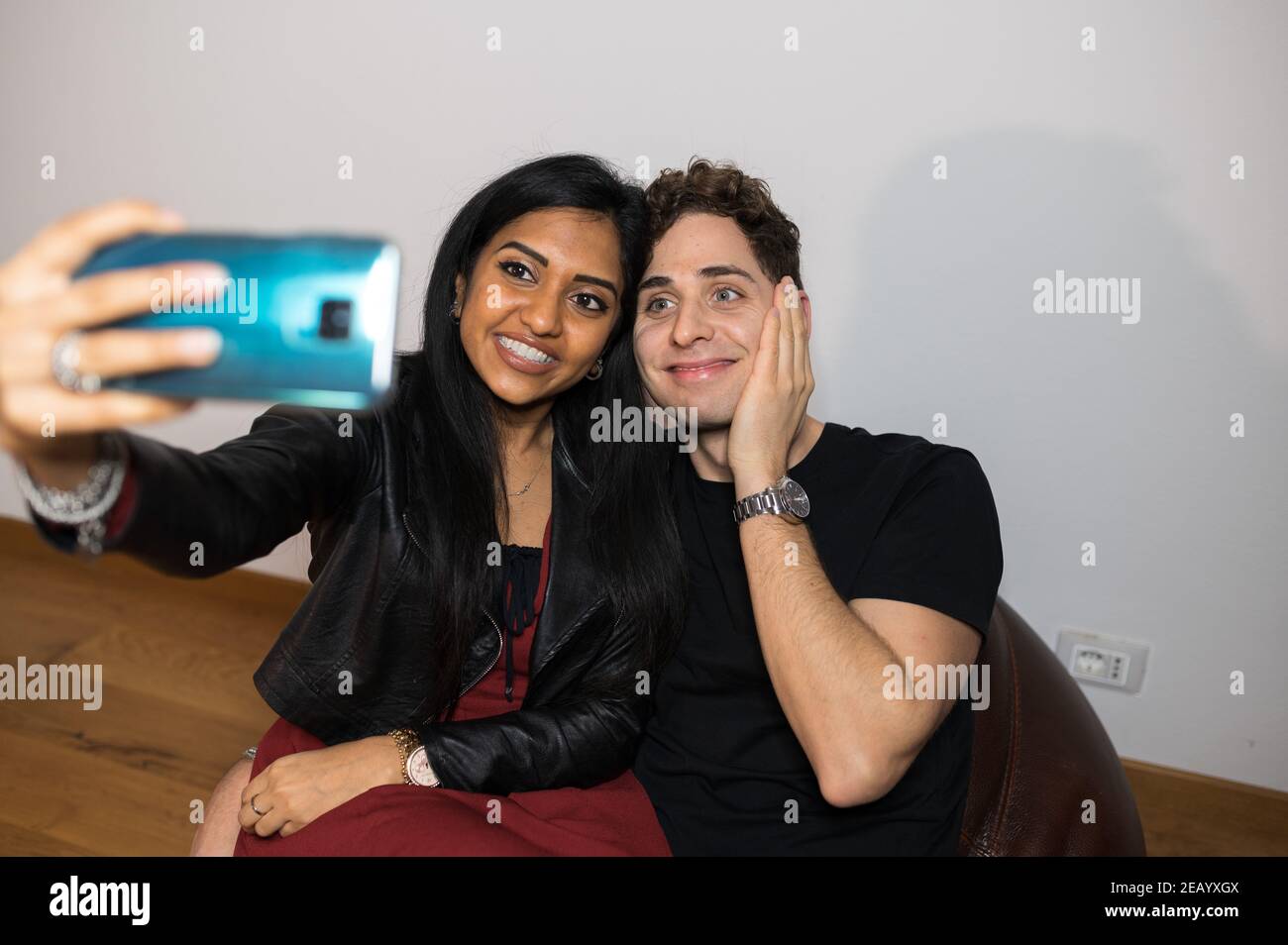 Fröhliche junge Paar nehmen ein Selbstporträt mit lustigen Gesicht zu Hause sitzen auf Bohnenbeutel. Stockfoto