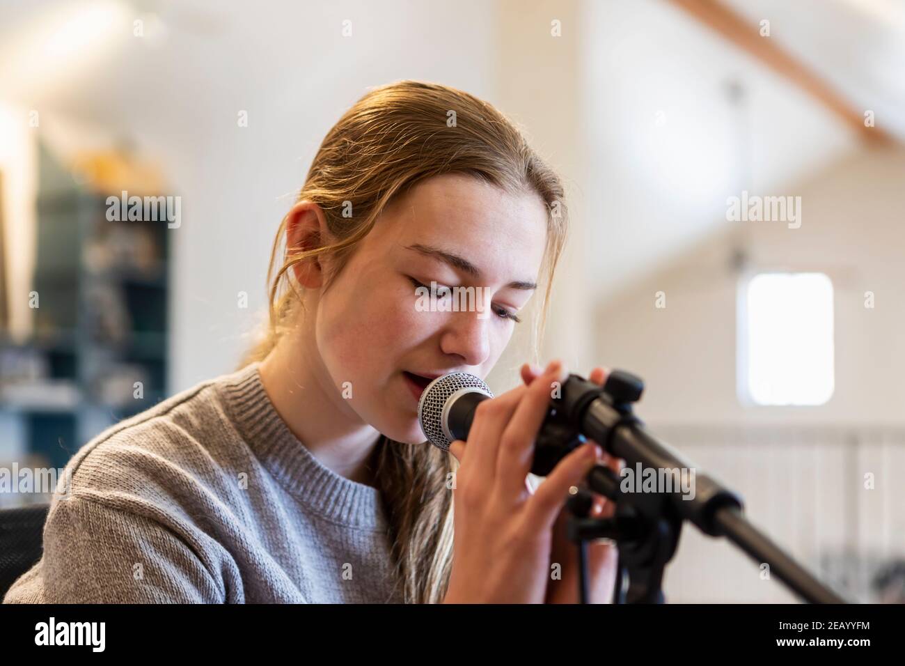 14 Jahre altes Teenager-Mädchen, das Gitarre spielt und singt Zu Hause im Loft Raum Stockfoto