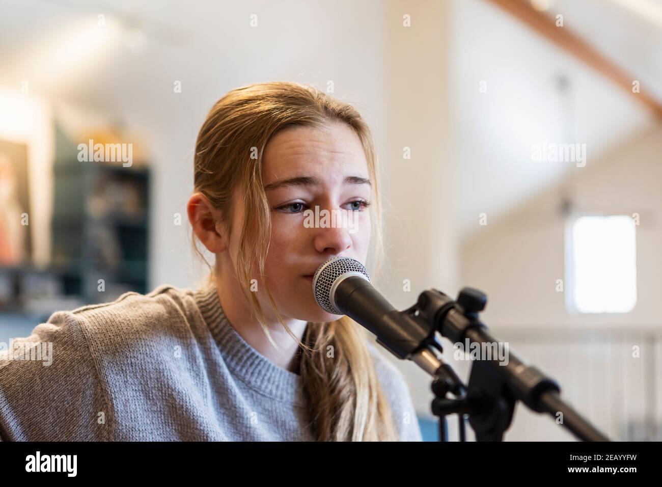 14 Jahre altes Teenager-Mädchen, das Gitarre spielt und singt Zu Hause im Loft Raum Stockfoto