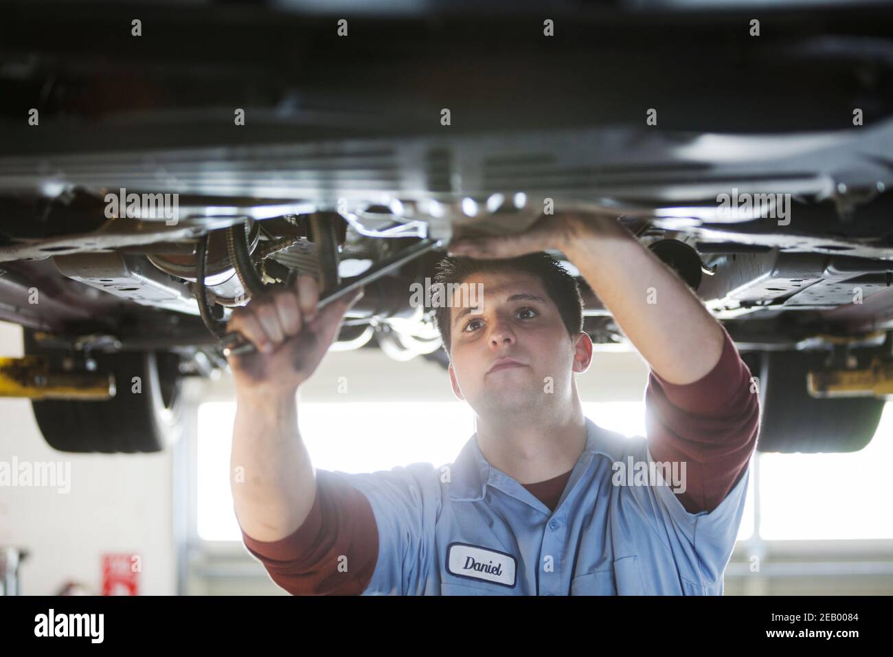 Mechaniker in einer Werkstatt arbeitet auf der Unterseite von Ein Auto auf einem Aufzug Stockfoto