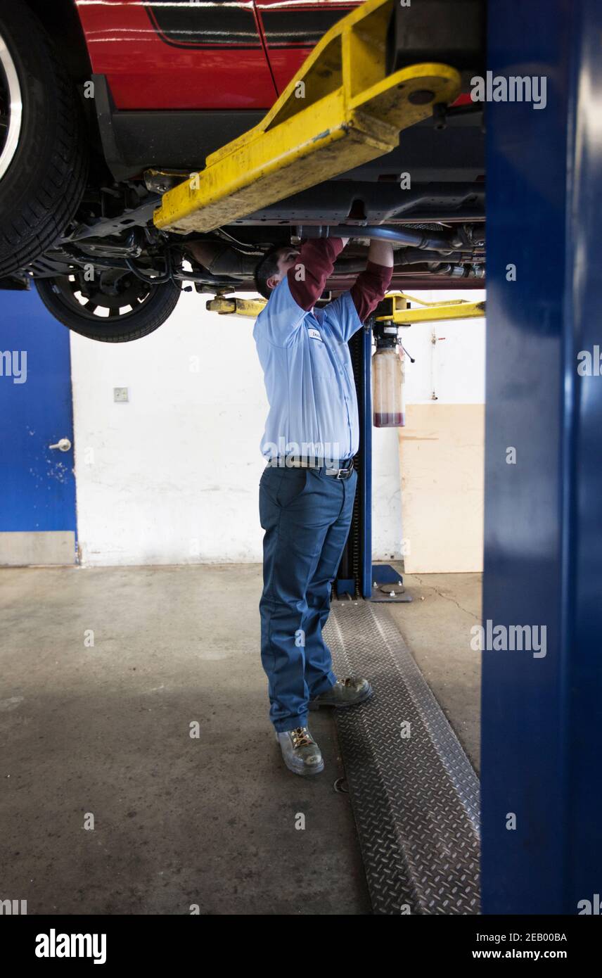 Mechaniker in einer Werkstatt arbeitet auf der Unterseite von Ein Auto auf einem Aufzug Stockfoto