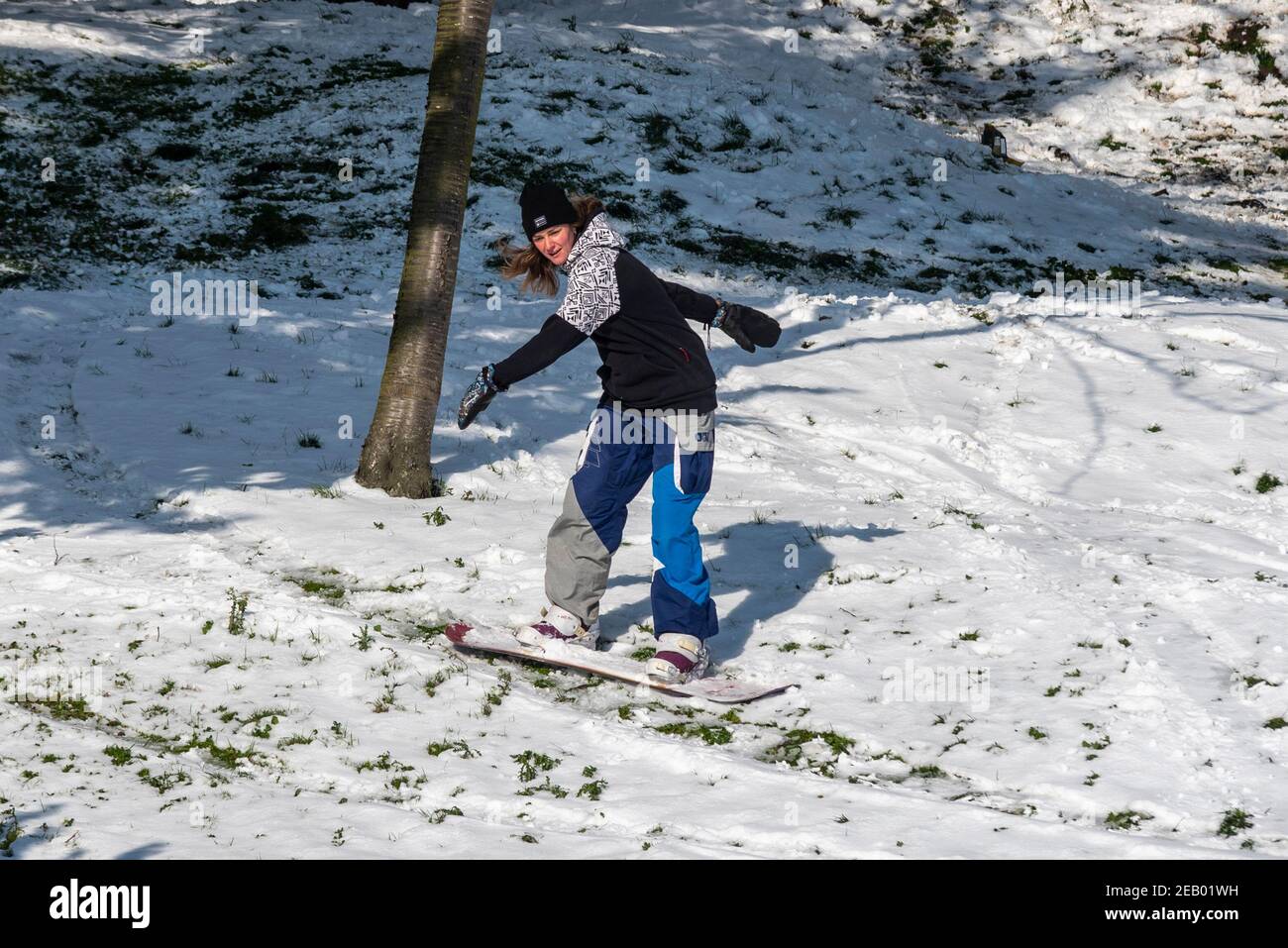Southend on Sea, Essex, Großbritannien. Februar 2021, 11th. Über Nacht fiel weiterer Schnee vom Sturm Darcy auf Southend. Die Leute sind draußen und genießen die Küste. Eine Snowboarderin boarding auf den schneebedeckten Cliff Gardens Stockfoto