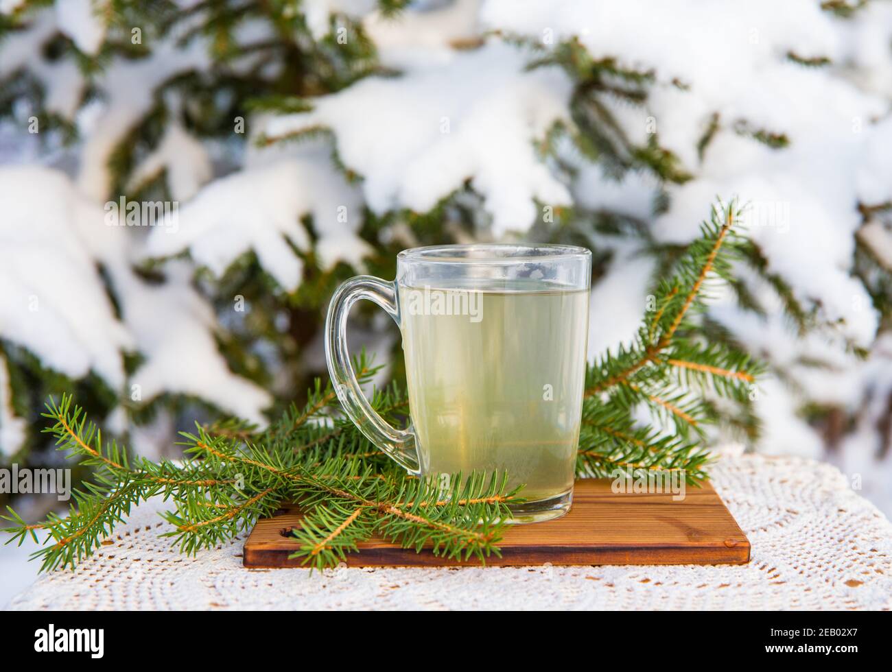 Fichtenbaum Nadel Tee Infusion in transparentem Glas Tee Tasse. Verschneite, verschwommene Fichte auf dem Hintergrund, draußen an kalten Wintertagen. Platz für Text. Stockfoto