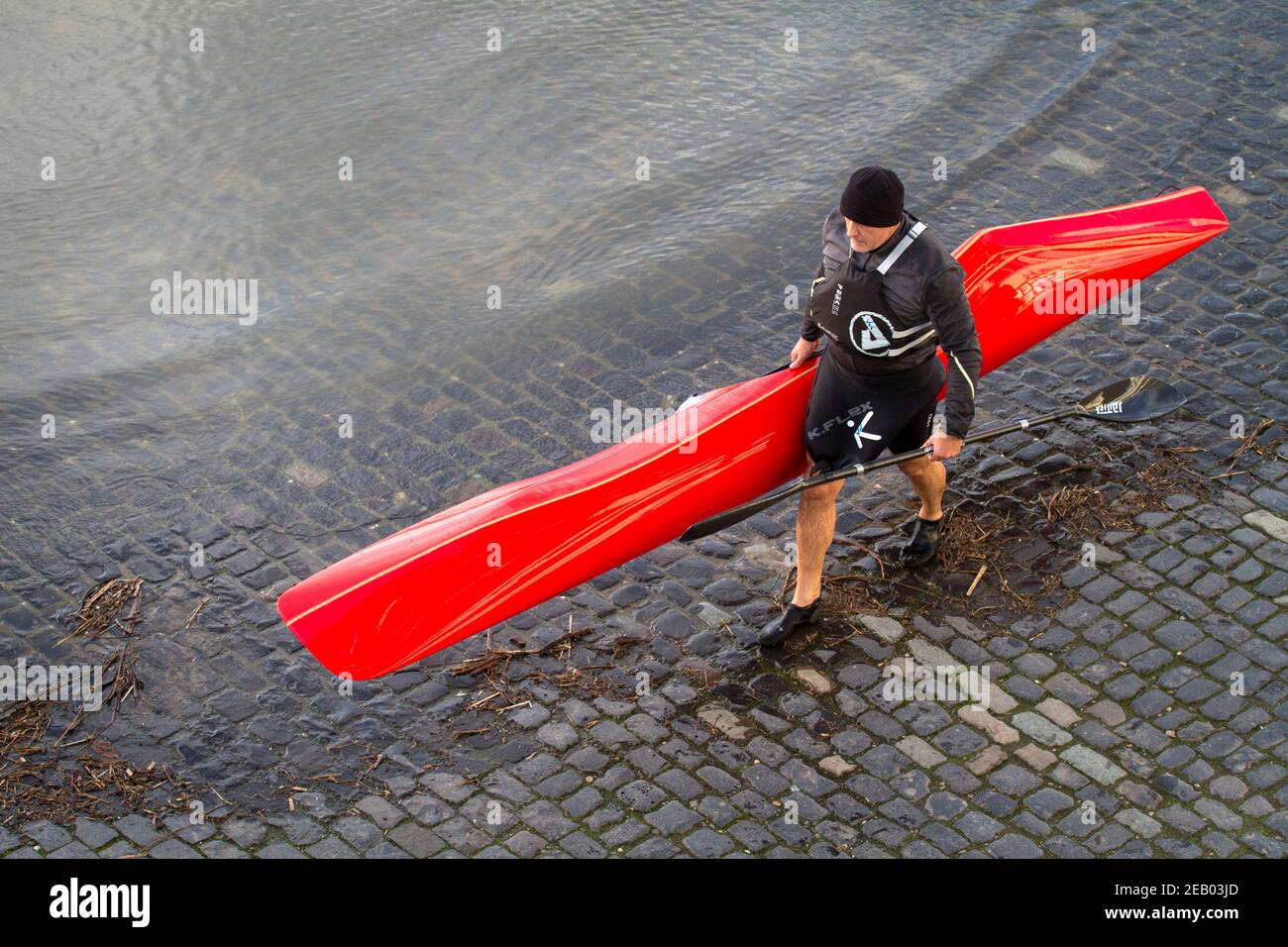 Mann, der sein Kajak zum Rheinufer in Deutz, Köln, trägt. Mann traegt sein Kajak an Rheinufer in Deutz, Köln, Deutschland. Stockfoto