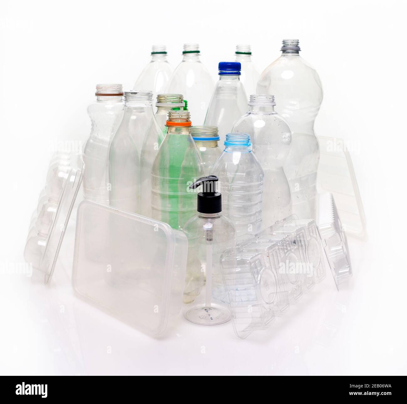 Eine Sammlung von Haushaltskunststoff auf Basis von Material auf weißem Hintergrund mit Reflexion aufgenommen. Flaschen, Lebensmittelschalen, Pumpbehälter bereit zum Recycling. Stockfoto