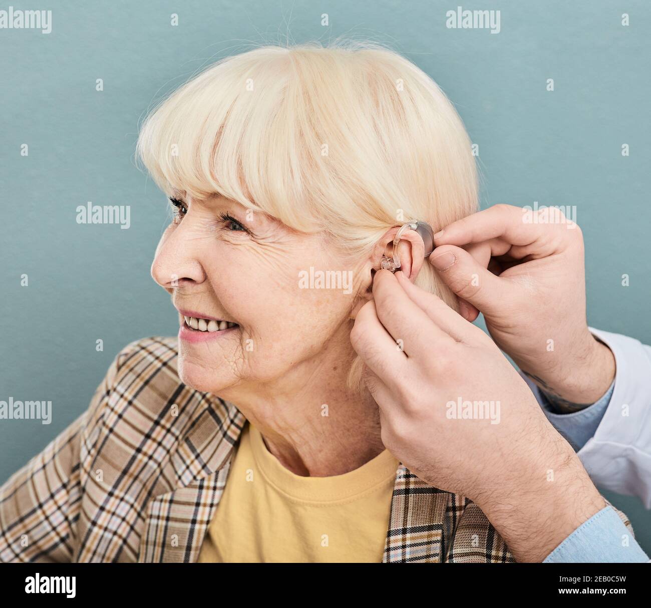 Schwerhörigkeit bei älteren Menschen, Hörlösung. Arzt, der Hörgerät auf das Ohr älterer Frauen einführt, Nahaufnahme Stockfoto