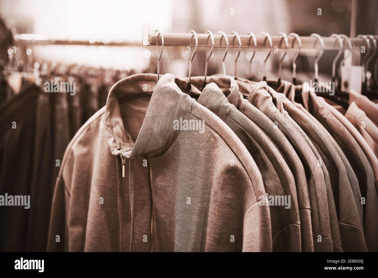 Hoodies mit hohem Hals hängen an Kleiderbügeln in einem Bekleidungsgeschäft in einem Einkaufszentrum. Zeit für einen Kauf. Verkauf von modischer Kleidung. Stockfoto