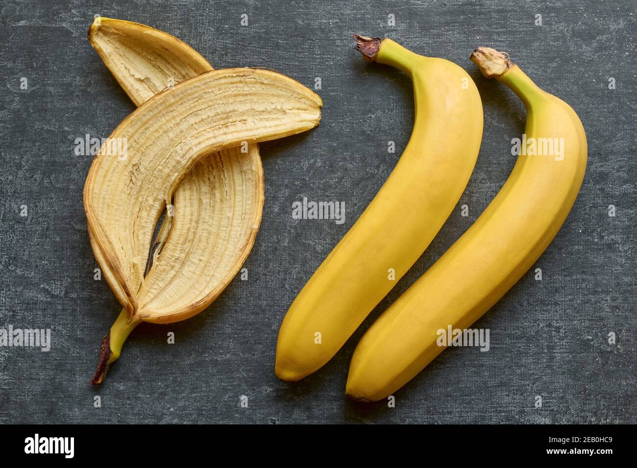 Bananenhaut und zwei ganze Bananen werden auf einem isoliert Grauer Hintergrund Stockfoto
