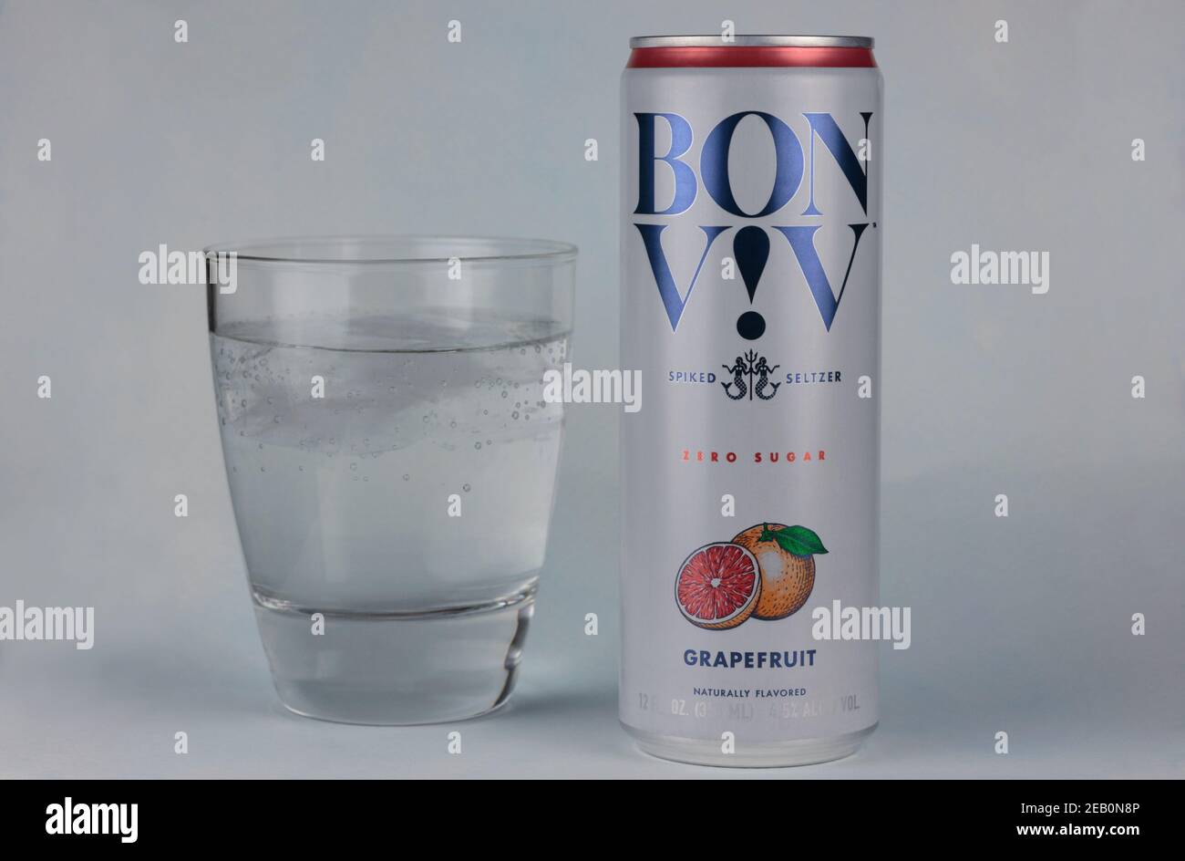 Dose und Glas Bon Viv Marke Spiked Seltzer, harte Seltzerwasser mit Alkohol hinzugefügt, ein beliebtes Getränk, auf einem hellblauen Hintergrund Stockfoto