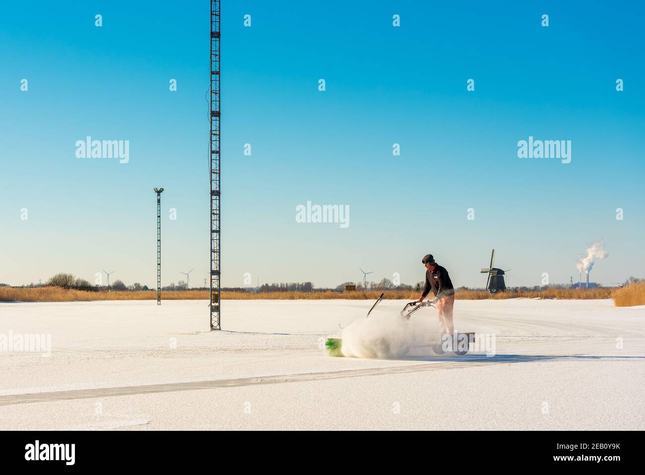 Mitglied des Eislaufvereins stäubt Schnee von Natur aus Eislaufbahn auf einem untergetauchten Fußballplatz in Grootschermer Niederlande im Februar 2021 Stockfoto