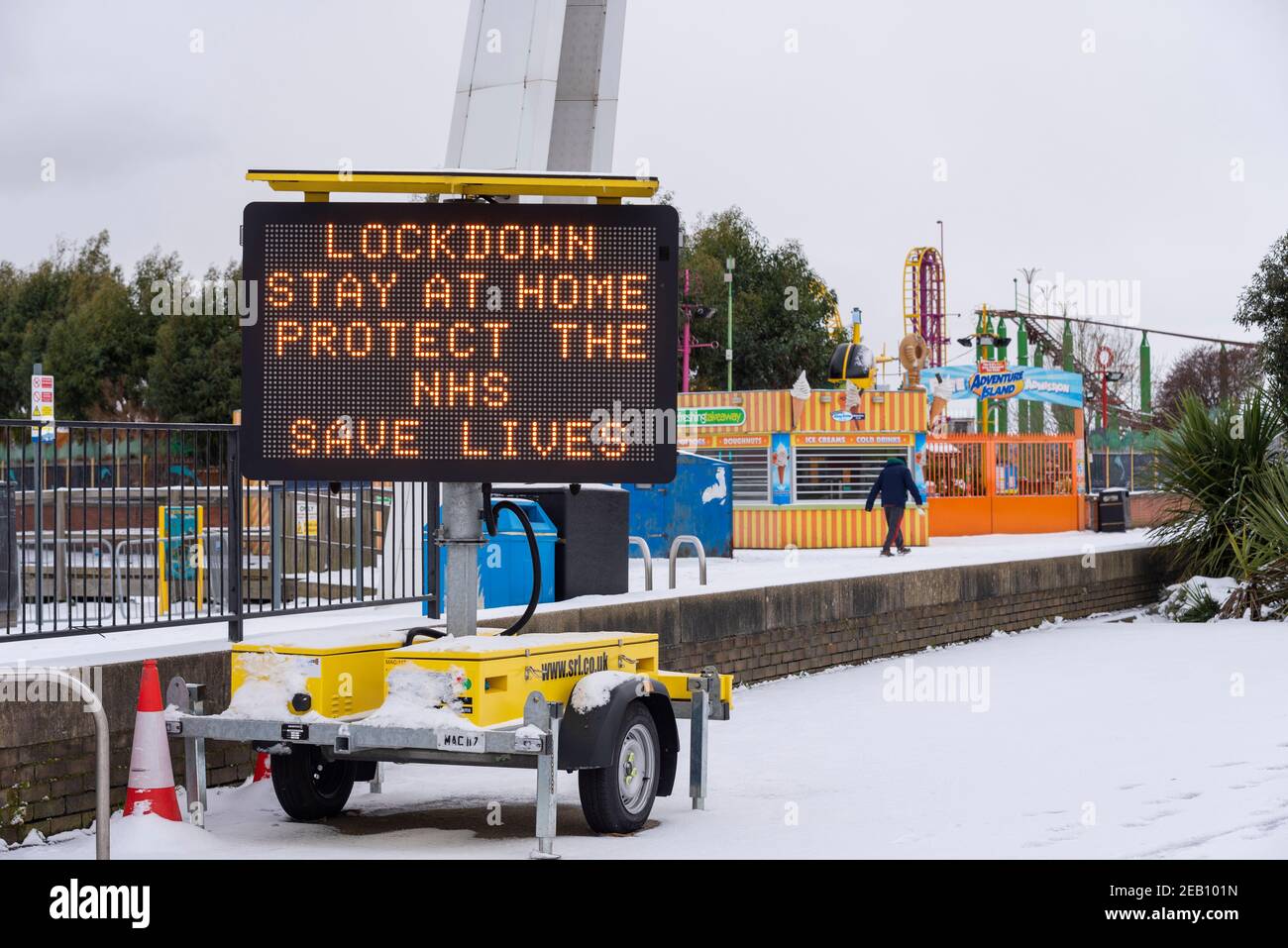 COVID 19 Pandemie-Sperrwarnschild in Southend on Sea, Essex, Großbritannien, mit Schnee von Storm Darcy. Richtlinien. Einflügger, der an Geschäften vorbeigeht Stockfoto