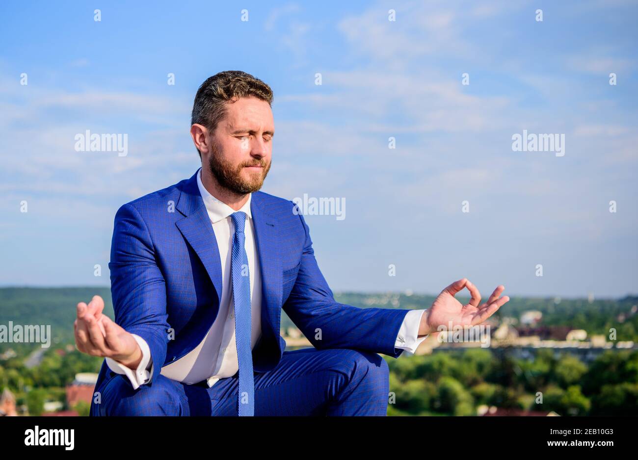 Geschäftsmann formelle Anzug sitzen Lotuspose und meditieren im Freien. Unternehmer finden Minute zum Entspannen und Meditieren. Der Mensch versucht, seinen Geist frei zu halten. Entspannungstechnik. Ruhe in seiner Seele bewahren. Stockfoto