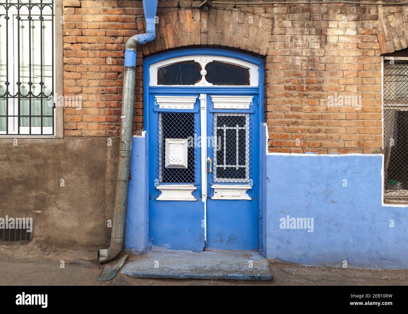 Vintage blau weiß Holztür in gelben Ziegelwand. Alte Tiflis Architektur, Georgien Stockfoto