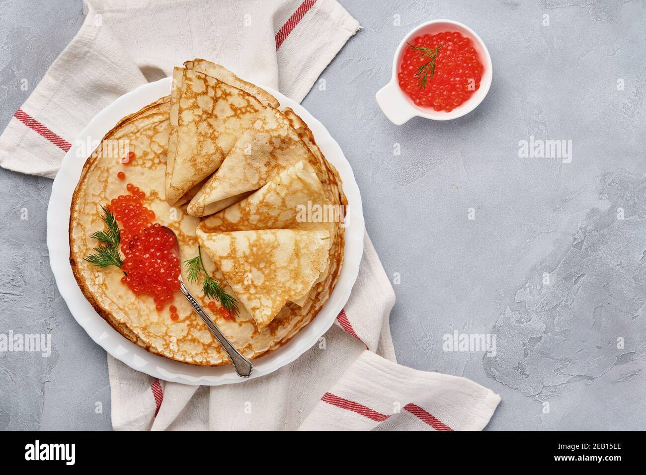 Crepes, dünne Pfannkuchen, russische Pfannkuchen mit rotem Kaviar auf grauem Teller. Marmorhintergrund. Speicherplatz kopieren. Draufsicht. Stockfoto