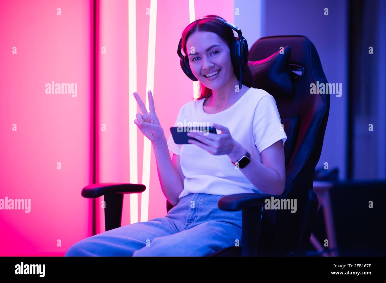 Junge weibliche professionelle Cybersport-Gamer spielen mobile Spiel mit dem Smartphone auf eSport Turnier online in bunten Neonlicht Zimmer. Stockfoto