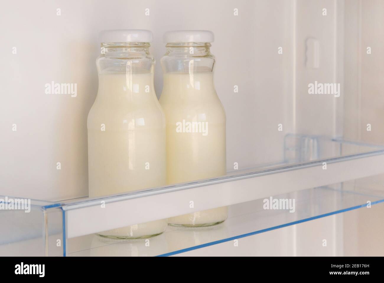 Joghurt in weißen Flaschen auf dem Regal des offenen leeren Kühlschranks. Gewichtsverlust Diät-Konzept. Fermentierte Lebensmittel. Stockfoto