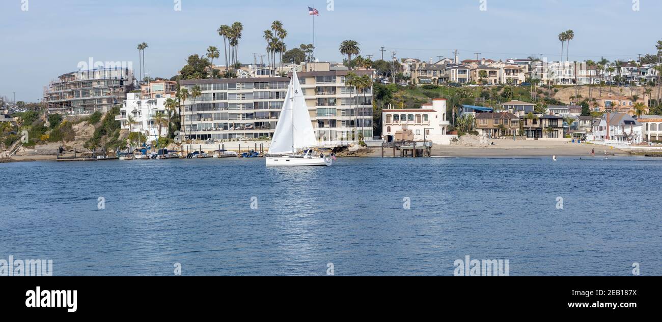 Segelboot in den Hafen von Newport Beach mit Häusern am Wasser Kalifornien, USA Stockfoto