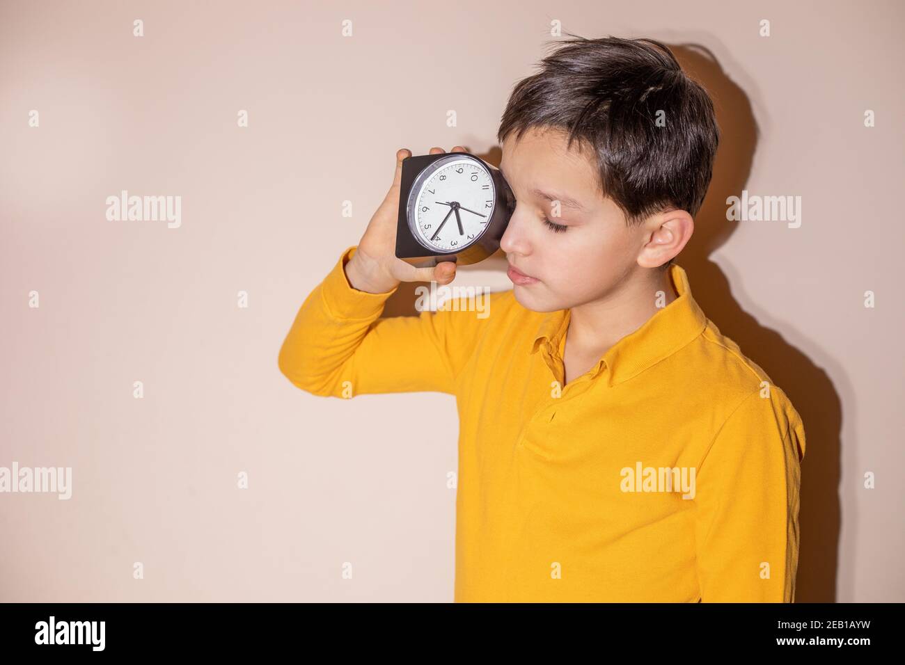 Teenager Kind Junge hält Wecker in den Händen und schlafen unterwegs, Nacht. Konzept der Schlafstörung bei Kindern und Jugendlichen. Hartes Licht Stockfoto