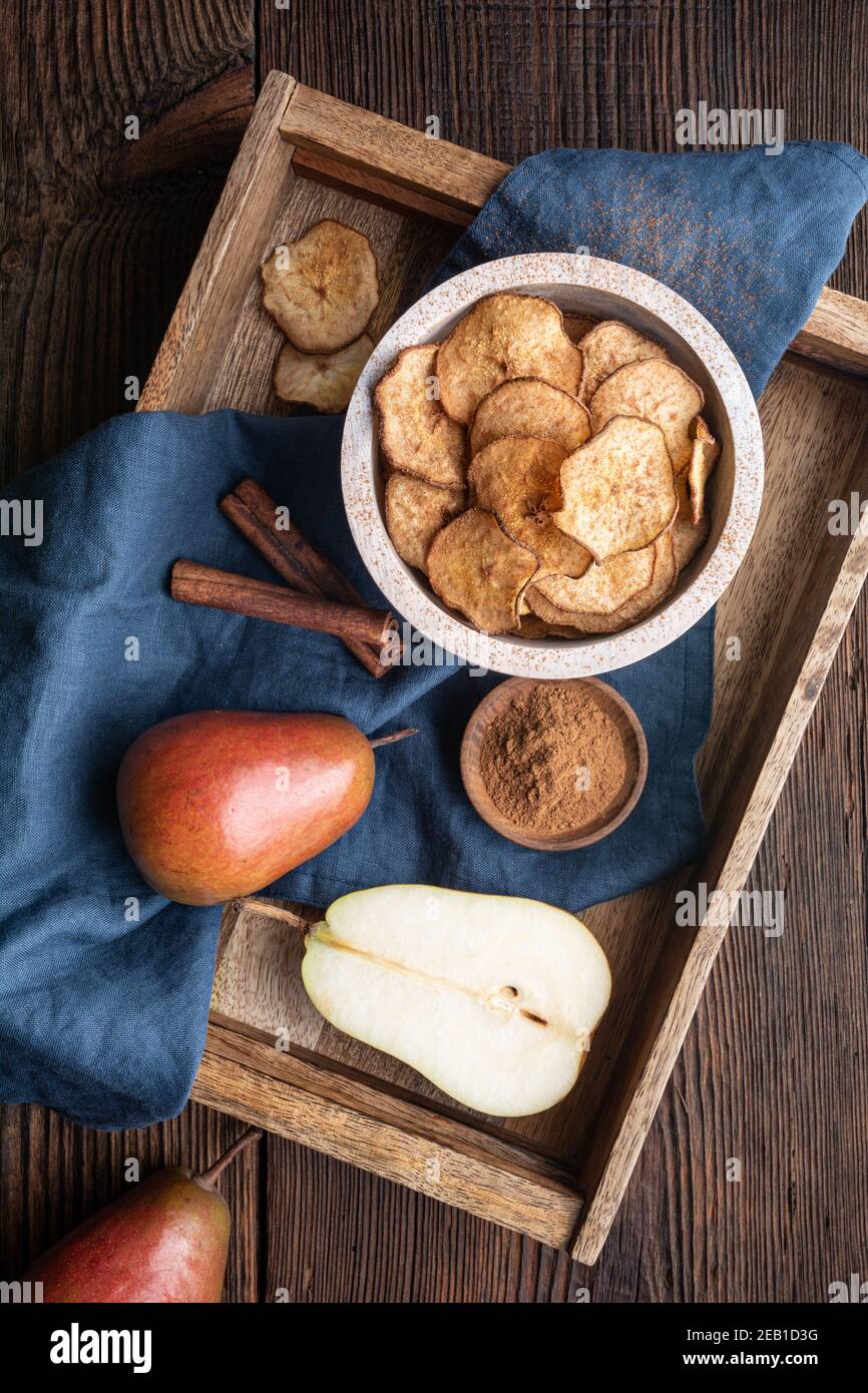 Süßer leckerer Snack, hausgemachter Ofen getrocknete knusprige Birnenchips mit Zimt auf rustikalem Holzhintergrund bestreut Stockfoto