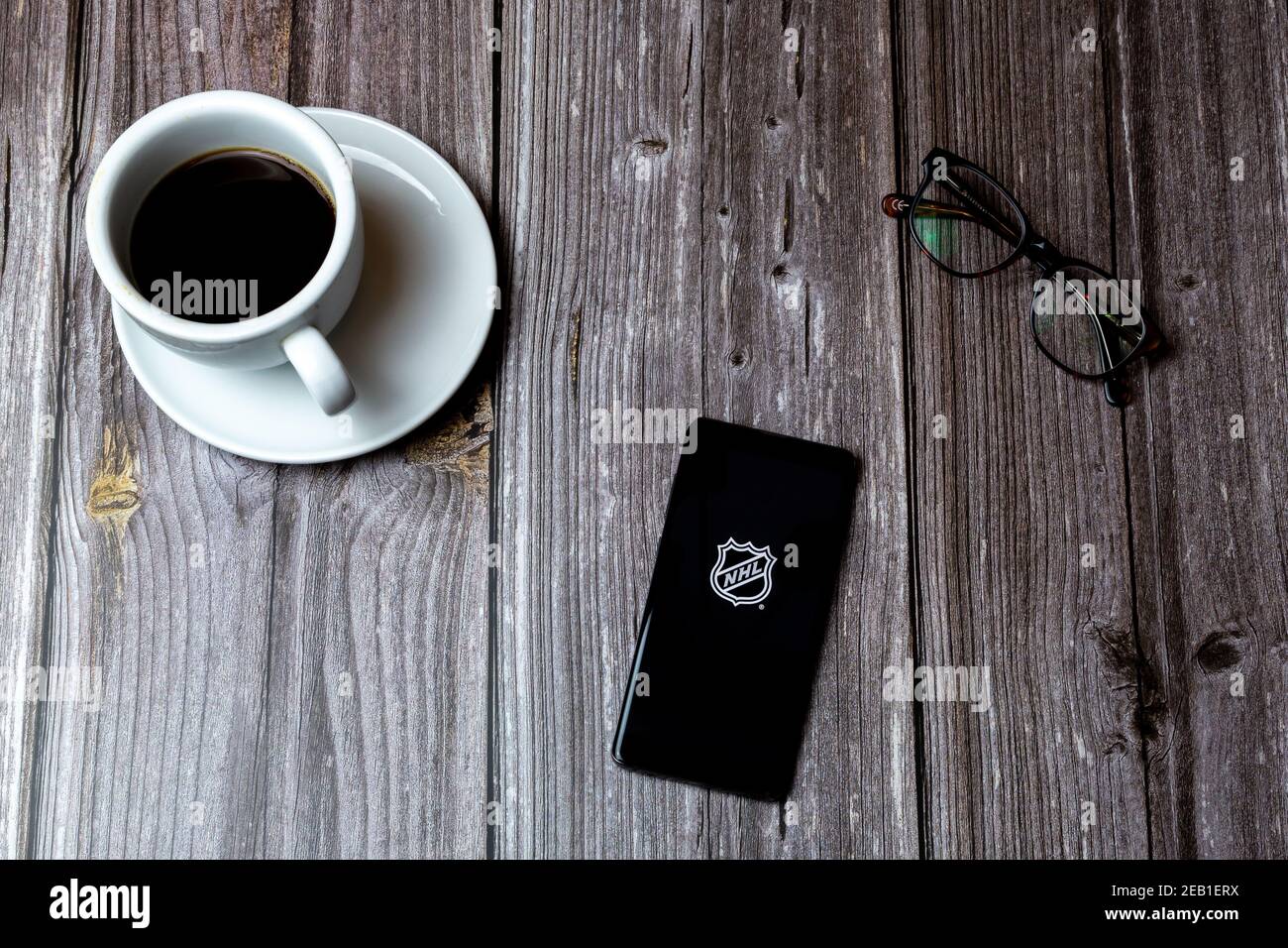 Ein Handy oder Handy auf einem Holz gelegt Tabelle mit der NHL Hockey App auf dem Bildschirm als nächstes geöffnet Zu einem Kaffee Stockfoto