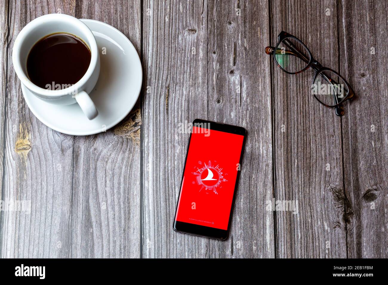 Ein Handy oder Handy auf einem Holz gelegt Tabelle mit der App der türkischen Fluggesellschaften auf dem nächsten Bildschirm geöffnet Zu einem Kaffee Stockfoto