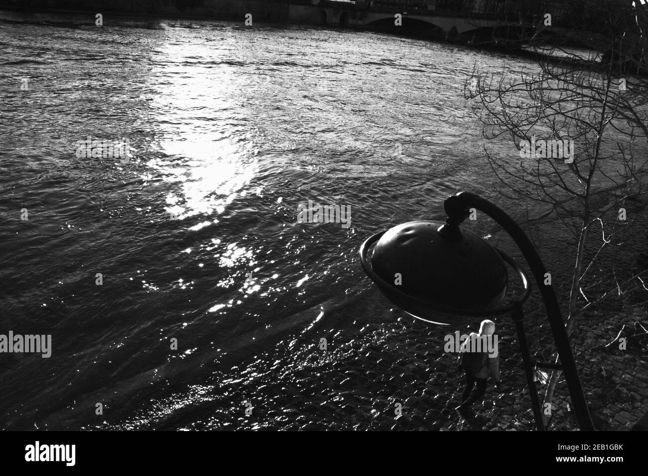 Hochwasser in Paris, Frankreich. Quay Park. Junge Frau (Rückansicht), die während des Hochwassers in der seine auf nassem Damm läuft. Schwarzweiß-Foto. Stockfoto