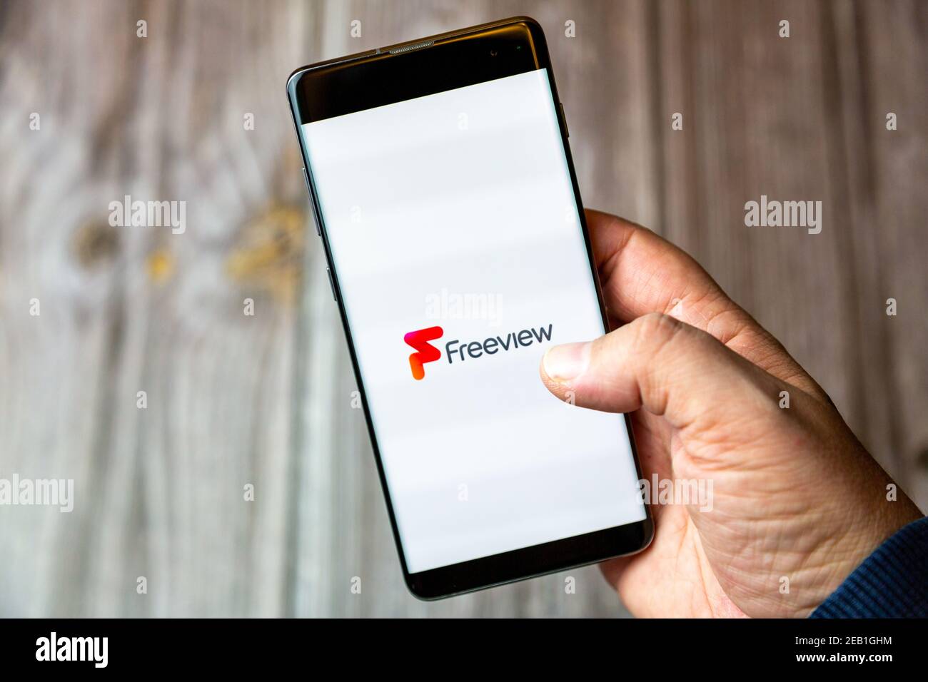 Ein Mobiltelefon oder Mobiltelefon, das von einem gehalten wird Hand mit der Freeview TV App geöffnet auf dem Bildschirm Stockfoto