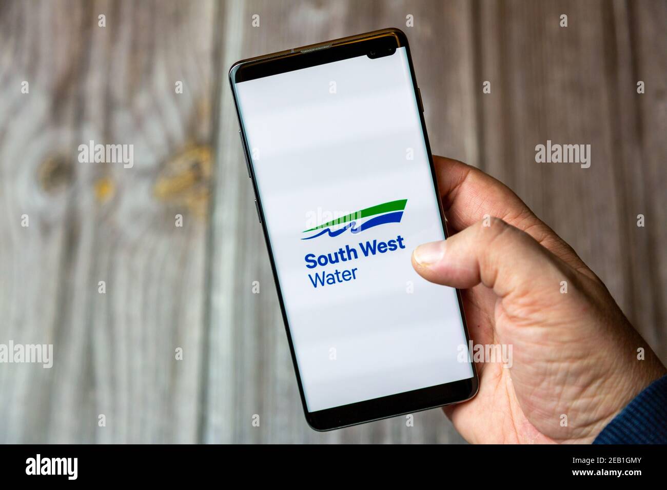 Ein Mobiltelefon oder Mobiltelefon, das von einem gehalten wird Hand mit der South West Water App auf dem Bildschirm geöffnet Stockfoto