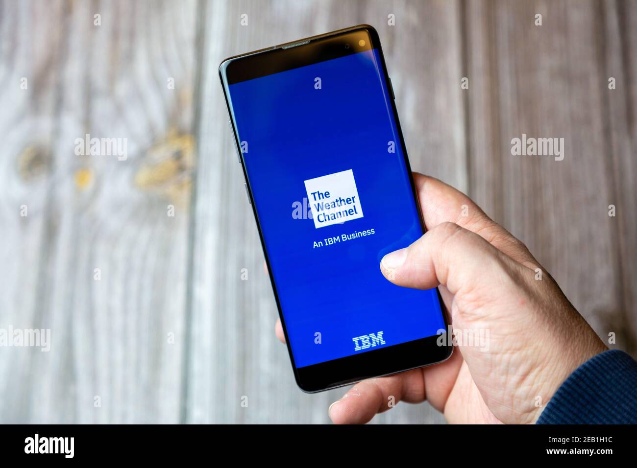 Ein Mobiltelefon oder Mobiltelefon, das von einem gehalten wird Hand mit der Wetter-Kanal-App auf dem Bildschirm geöffnet Stockfoto