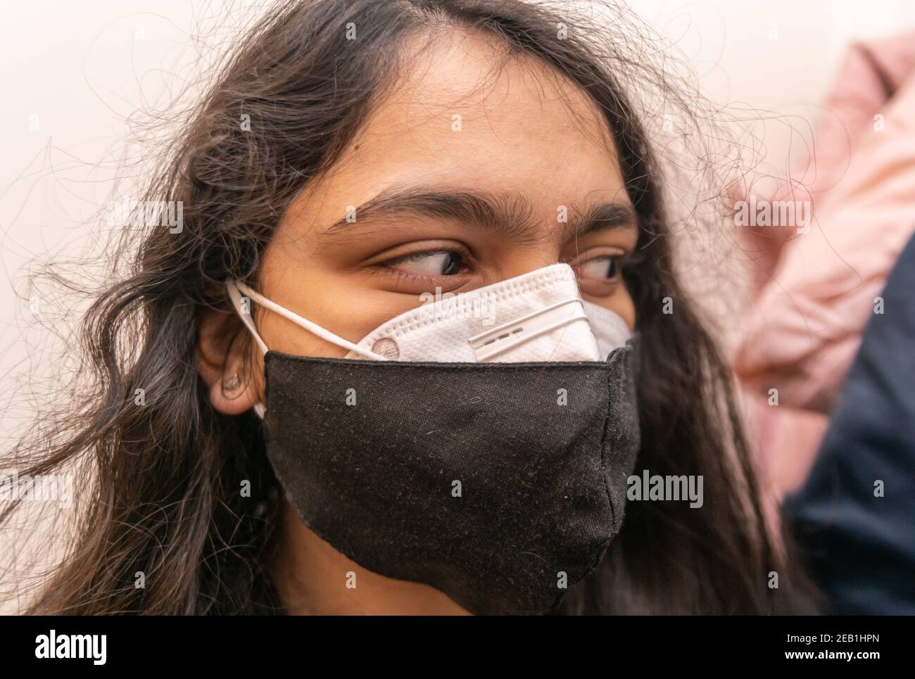 Indische Frau trägt zwei Gesichtsmasken, eine N95 und eine Stoffmaske für covid-19 Prävention. Doppelmaskierung wird von der US-amerikanischen CDC vorgeschlagen. Stockfoto
