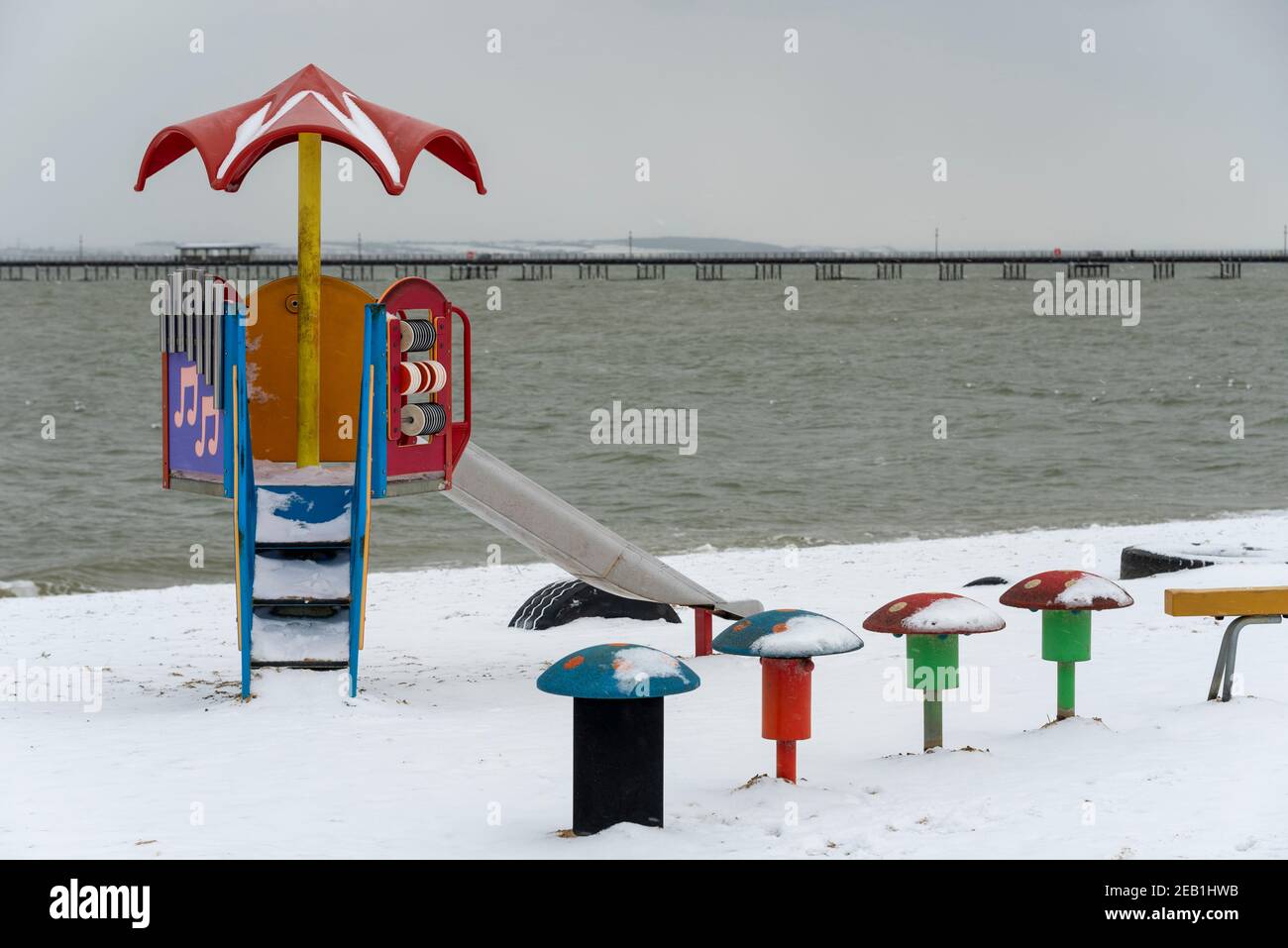 Strandspielplatz in Southend on Sea, Essex, Großbritannien, mit Schnee von Storm Darcy. Schneebedeckter Strand. Kinderrutsche und Kindersitze Stockfoto