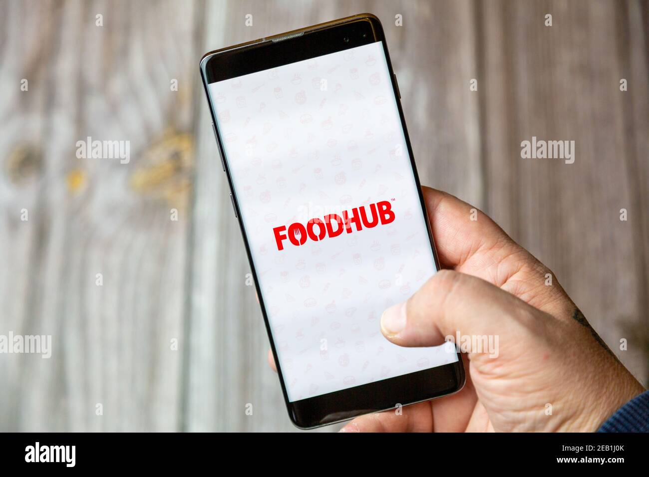 Ein Mobiltelefon oder Mobiltelefon, das von einem gehalten wird Hand mit der Foodhub App auf dem Bildschirm geöffnet Stockfoto
