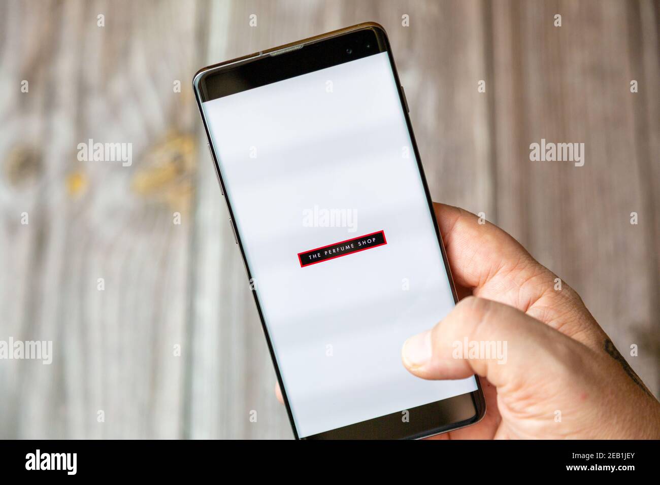 Ein Mobiltelefon oder Mobiltelefon, das von einem gehalten wird Hand mit der Parfüm Shop App auf dem Bildschirm geöffnet Stockfoto