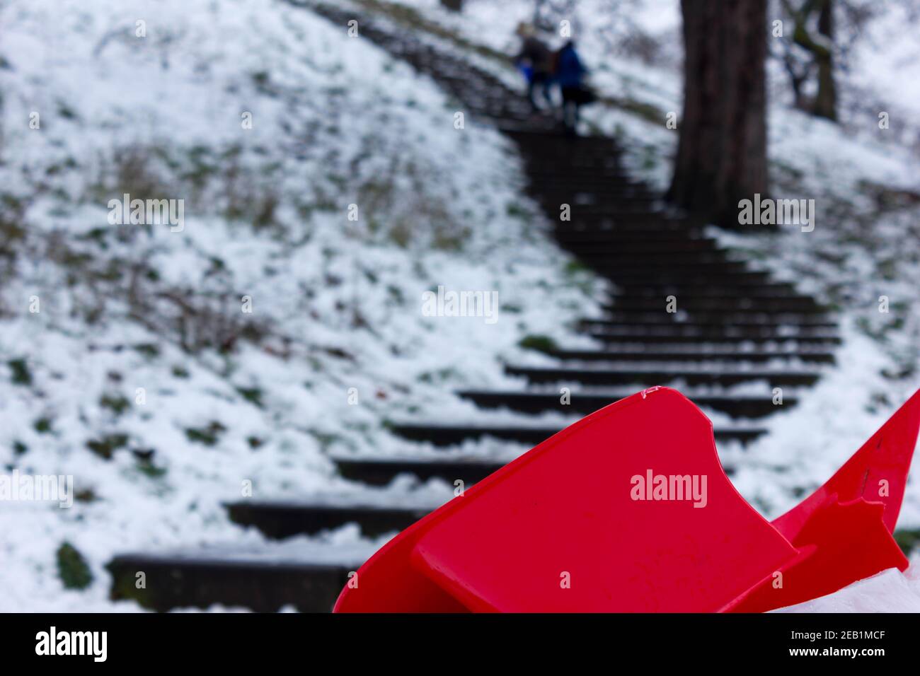 Zerbrochener roter Schlitten, der am Fuß der Stufen zur Hügelspitze im London Greenwich Park, England, aufgegeben wurde Stockfoto