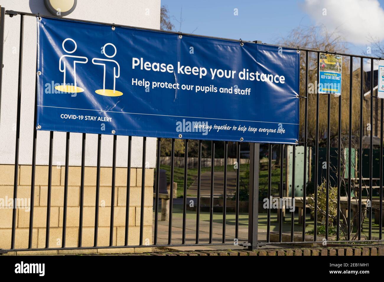Bitte halten Sie Ihren Abstand Banner fest, um Schulzaun zu Schüler und Mitarbeiter schützen Stockfoto