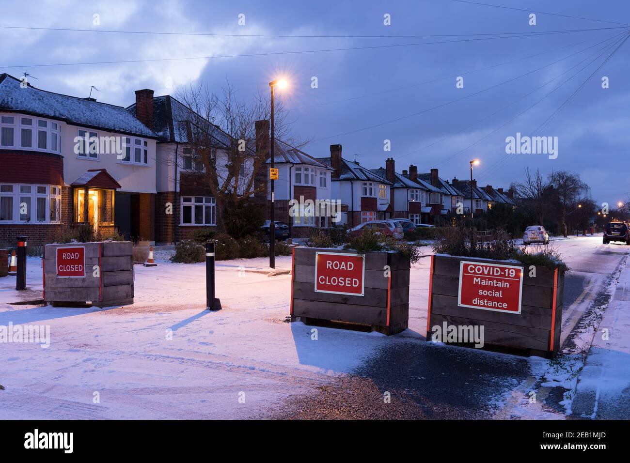 Drei hölzerne Pflanzer zeigen Straße geschlossen Zeichen auf Schnee bedeckt Straße in London Stockfoto