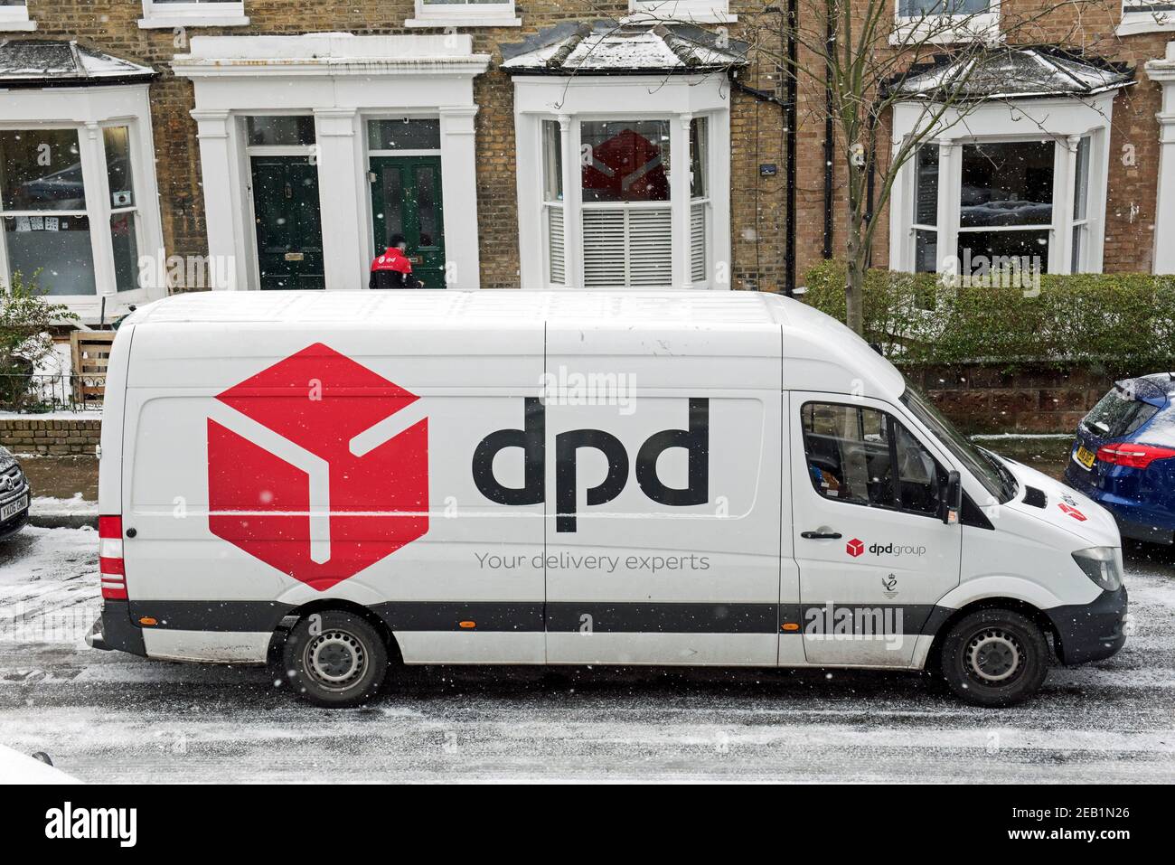 dpd Delivery Van mit Fahrer in Snow Lieferung an Reihenhaus in Urban Street, Lower Holloway, London Borough of Islington, England Großbritannien Stockfoto