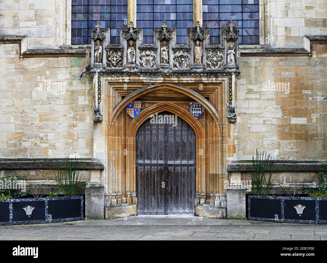 Eingang aus Holz mit Wappen und Statuen, Magdalene College, University of Oxford, England. Gewölbte Holztür Stockfoto