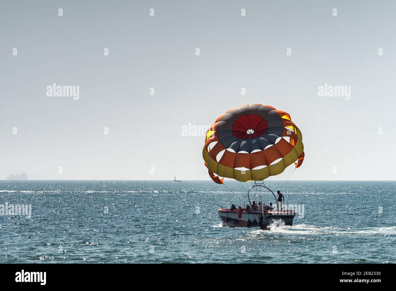 Nicht erkennbare Leute bereiten sich auf dem Boot auf Parasailing vor, fliegen bald. Selektiver Fokus auf Fallschirm. Konzept des Urlaubs, Extremsport am Strand Stockfoto
