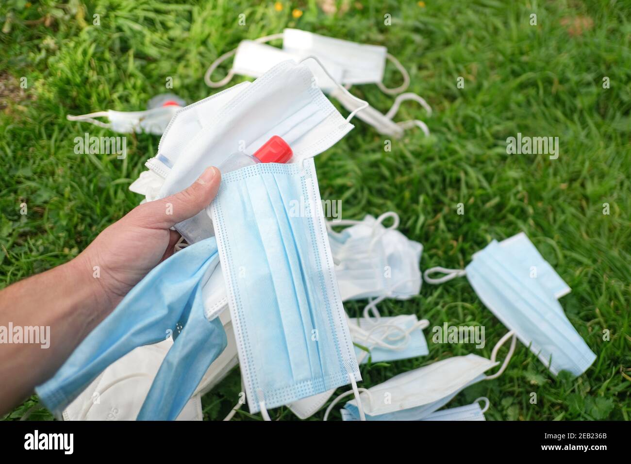 Gebrauchte Gesichtsschutzmaske und Handdesinfektionsflasche auf entsorgt Natürliches Ökosystem,covid19 pandemische Abfallverschmutzung Stockfoto