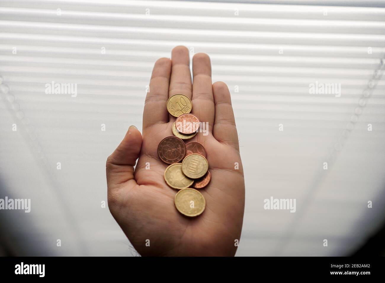 Münzen, Groschen in der Hand. Euro 10 Cent auf der Handfläche mit Hintergrundbeleuchtung aus dem Fenster. Die letzte der Einsparungen. Stockfoto