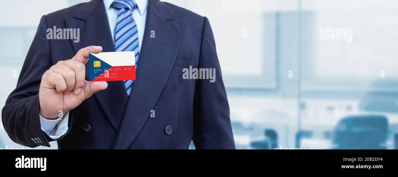 Zugeschnittenes Bild des Geschäftsmannes mit Plastikkreditkarte mit gedruckter Flagge der Tschechischen Republik. Hintergrund unscharf. Stockfoto