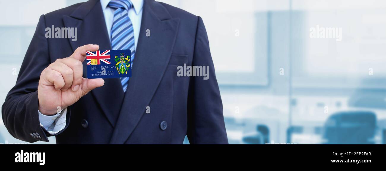 Zugeschnittenes Bild eines Geschäftsmannes, der eine Plastikkreditkarte mit bedruckter Flagge der Pitcairn-Inseln hält. Hintergrund unscharf. Stockfoto