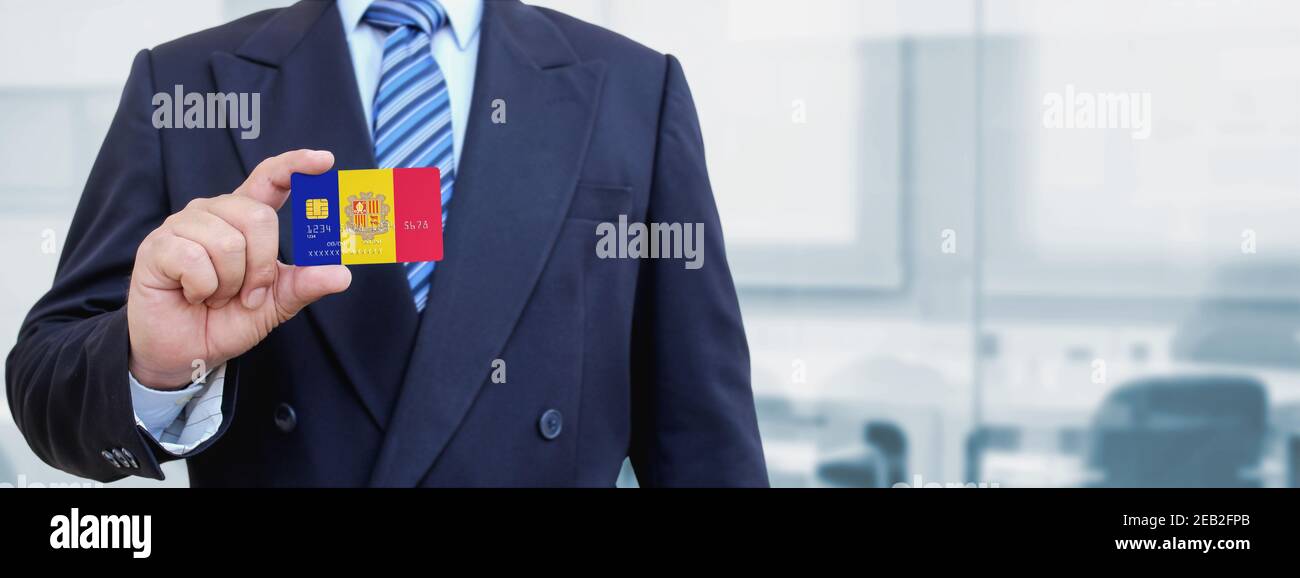 Zugeschnittenes Bild des Geschäftsmannes, der eine Plastikkarte mit bedruckter Flagge Andorras hält. Hintergrund unscharf. Stockfoto