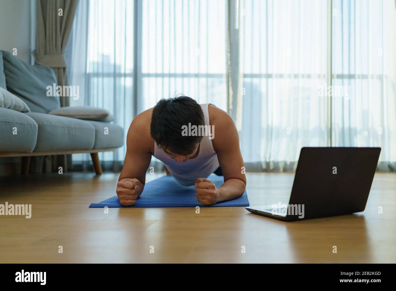 Asiatische Männer trainieren zu Hause, indem sie während des COVID-19-Ausbruchs in Sporthallen-Schließungen planken. Stockfoto