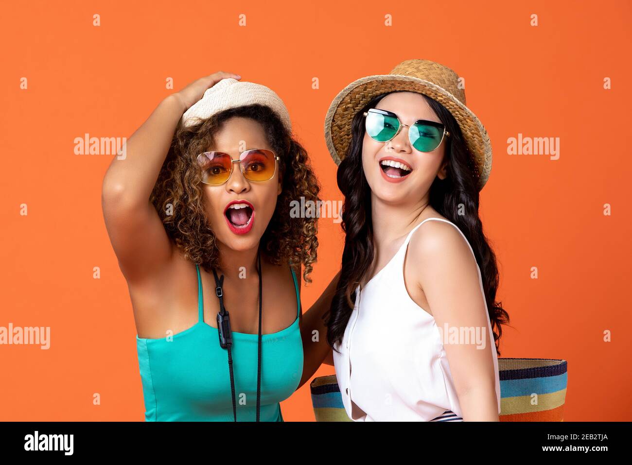 Glücklich ekstatisch interracial Frau Freunde im Sommer casual Outfits auf studio Koralle orange Hintergrund Stockfoto