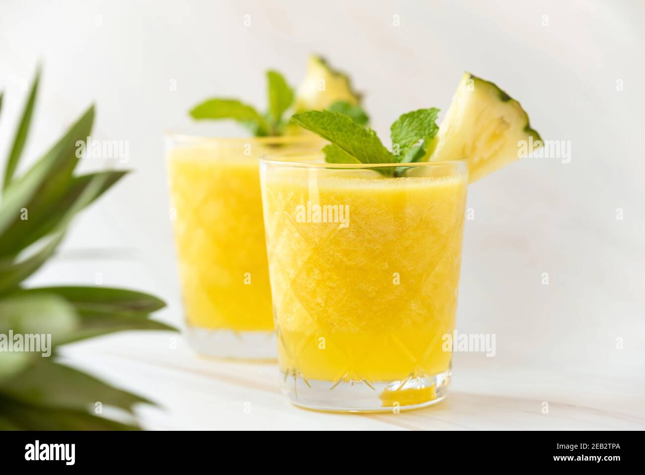 Erfrischende gesunde Ananasfrucht-Smoothie-Getränke auf der Arbeitsplatte aus weißem Marmor Stockfoto